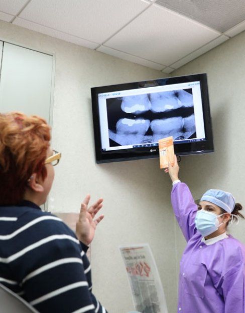 Dental team member and patient looking at digital x-rays