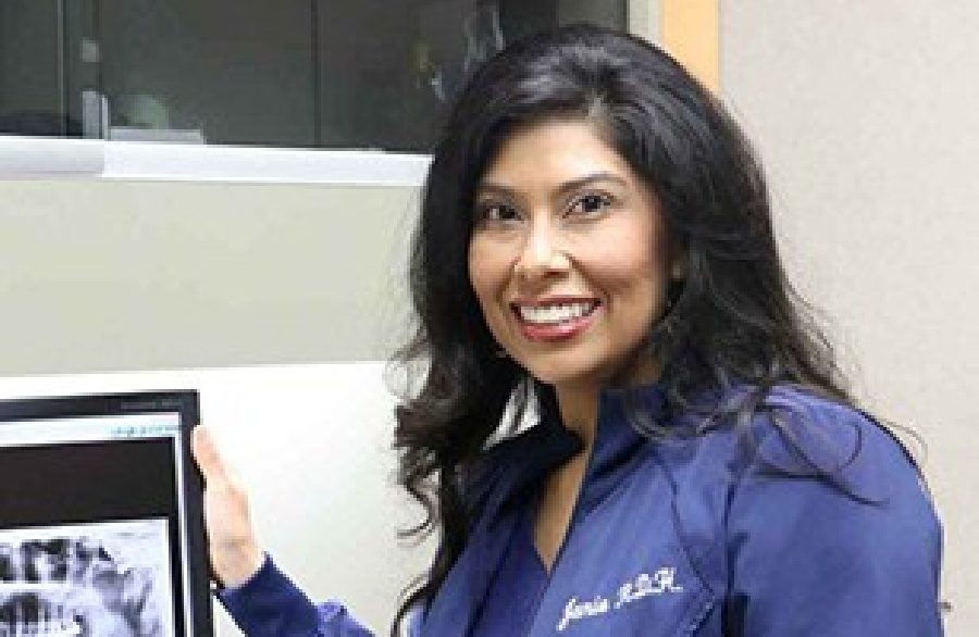 Smiling dental team member standing next to computer screen in Houston