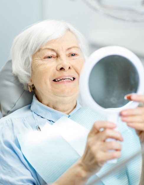 Woman with denture looking at her smile in the mirror