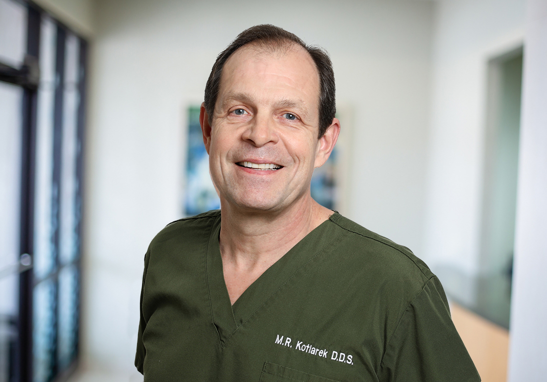 Houston Texas dentist Roman Kotlarek D D S wearing dark green scrubs