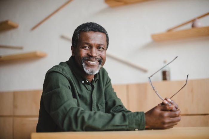 Smiling older man holding his glasses