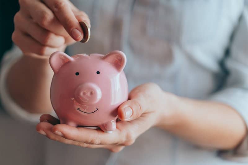 person putting coin in piggy bank in Houston