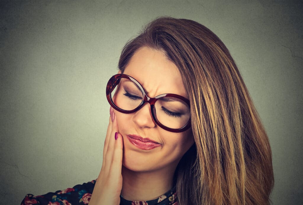 A woman experiencing tooth pain that could be resolved with a root canal