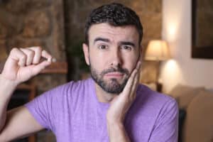 Adult man holding tooth that he lost and holding his jaw from pain