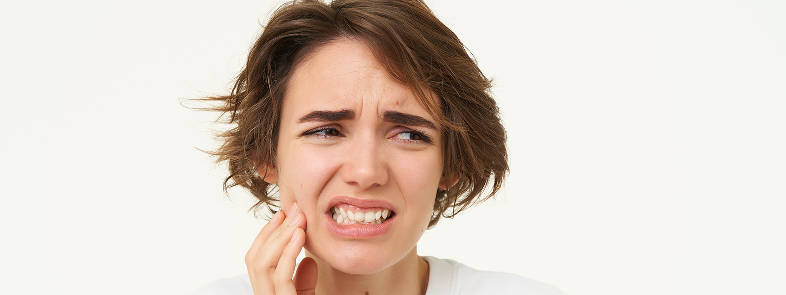 close up woman has toothache touches her teeth frowns from painful discomfort stands (1)