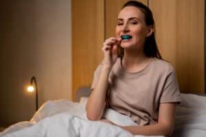 Woman putting on her custom nightguard to prevent teeth grinding