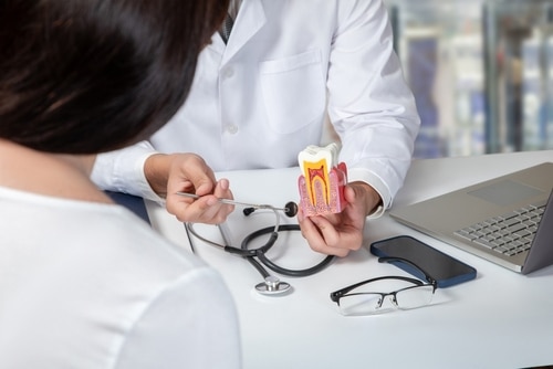 Doctor explaining the importance of a timely root canal to a patient during a consultation.