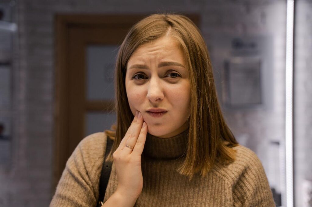 Woman with aching wisdom tooth considering wisdom tooth extraction