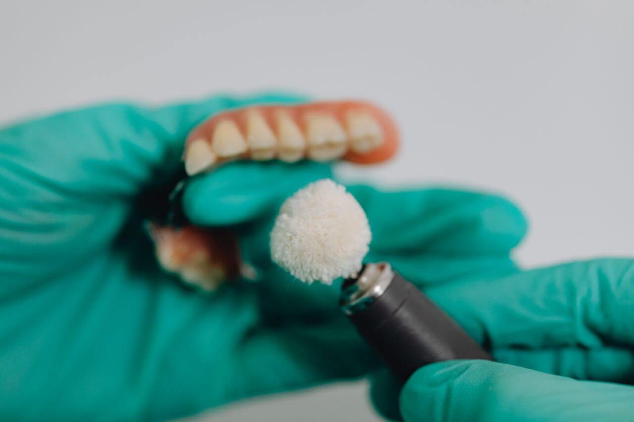 A dental professional wearing gloves polishing the dentures